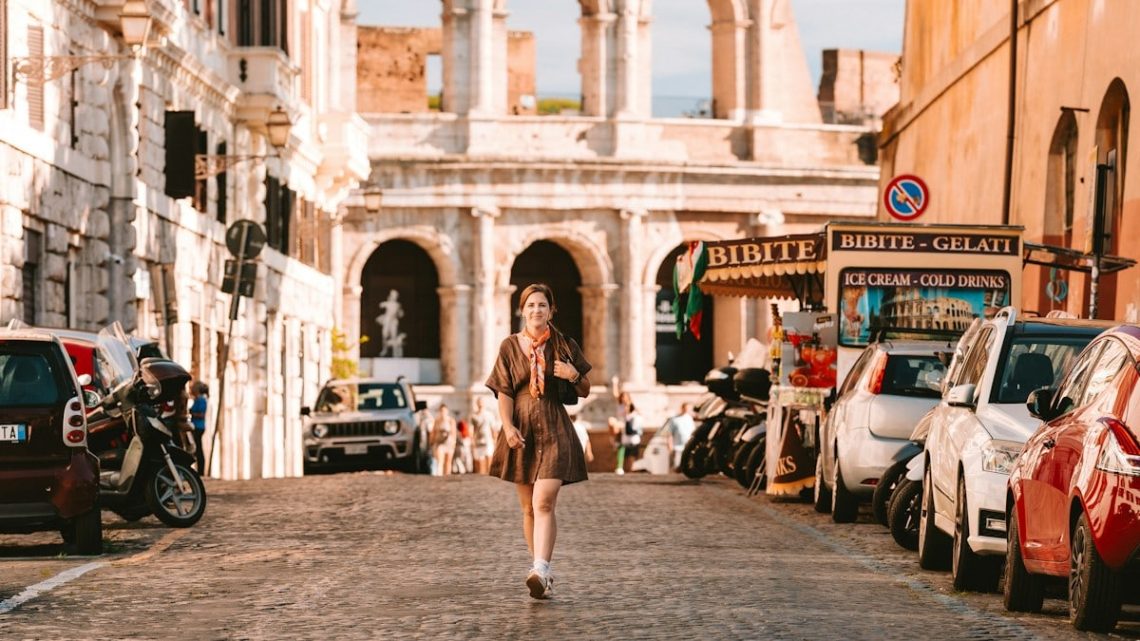 A woman walks along a cobblestone street near the Colosseum in Rome, Italy.