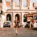 A woman walks along a cobblestone street near the Colosseum in Rome, Italy.